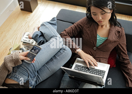 Two young women using their mobile phone and laptop Stock Photo
