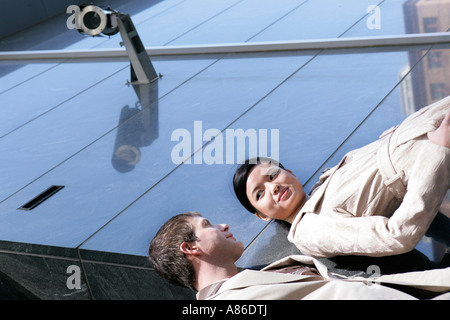 Man and asian woman talking on corner of building under surveillance camera Stock Photo