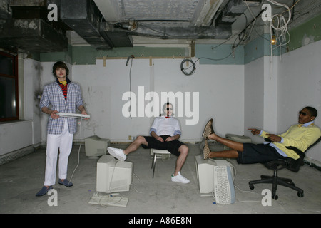 Three young men in an open space with old computers Stock Photo