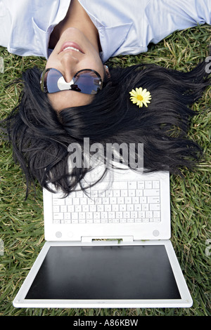 View of a woman sleeping on the grass with a flower in her hair. Stock Photo