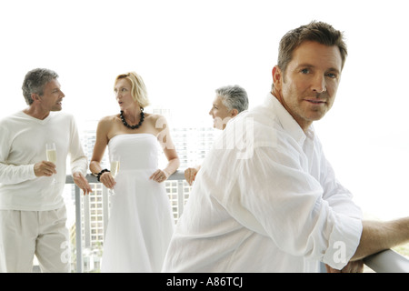 4 people on a terrace talking, man looking at camera Stock Photo