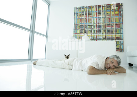 Mature man laying on the floor with a cat Stock Photo