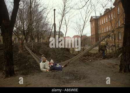 Christiania Copenhagen 1980s 80s Denmark Father and son sit in a hammock. Showing old military military barracks HOMER SYKES Stock Photo