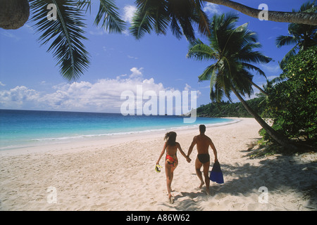 Couple running across white sands of Anse Intendance on Mahe Island in Seychelles Stock Photo