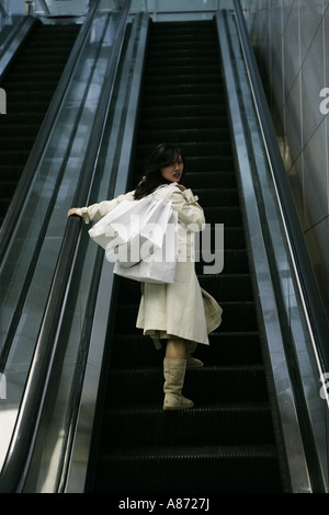 A young woman is standing on an escalator. Stock Photo