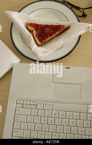 Laptop and slice of bread on plate, close-up Stock Photo