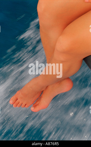 Close up of a pair of legs hanging from the edge of a boat Stock Photo