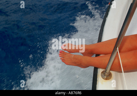 Close up of a pair of legs hanging from the edge of a boat Stock Photo
