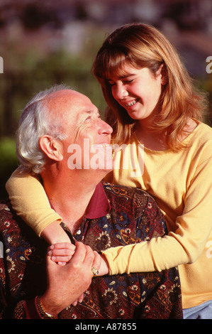 Caucasian young girl 11-13 year years old face to face standing behind grandfather hugging looking each other outdoors outside tween Tweens person Stock Photo