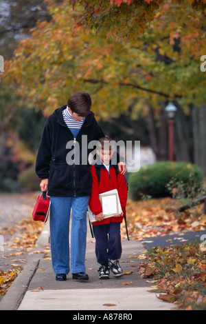 Mother walking young son home from school after a tough day at school Stock Photo