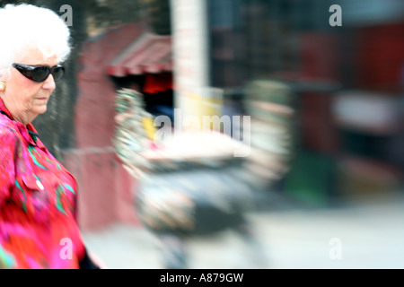 Impressionist Photograph of a Caucasian old lady walking past an incense pot outside a temple, Macau Stock Photo