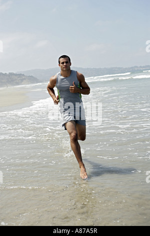 A young man is running on a beach. Stock Photo