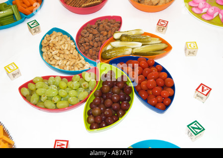 Snack food on table in bowls laid out with flowery spiral design for baby shower party. Stock Photo