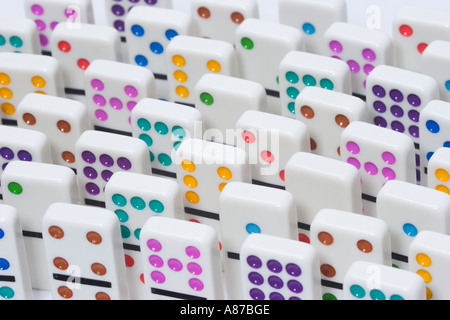 Uniform rows of white dominoes with brightly colored dots standing on end Stock Photo