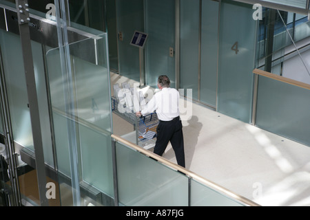 Mature man pushing trolley, rear view Stock Photo