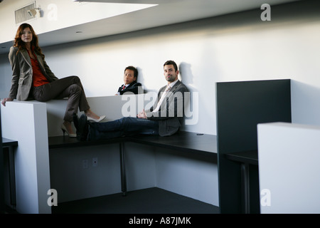 Three business people sitting on desks Stock Photo