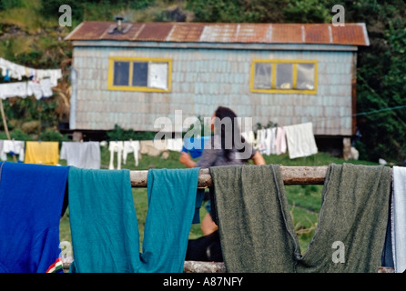 Clothes hanging in the yard of a typical home in La Arena Patagonia Chile with a Chilean woman running through yard Stock Photo
