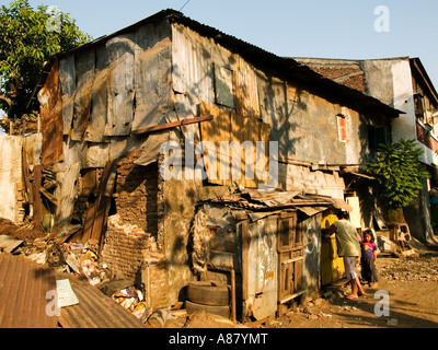 Mother and child enter their ramshackle shack like house in slum area,Surabaya,Java,Indonesia Stock Photo