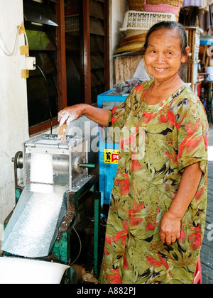 Smiling local woman grinding coconut in a mill,Yogyakarta,Java,Indonesia Stock Photo