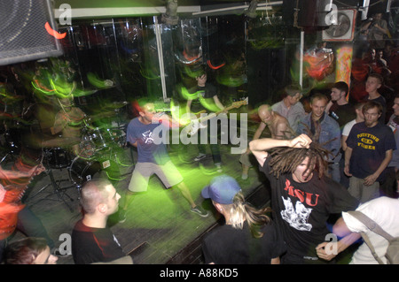 Hard core band concert in a small venue with a crowd moshing and musicians performing under green stage lights. Stock Photo