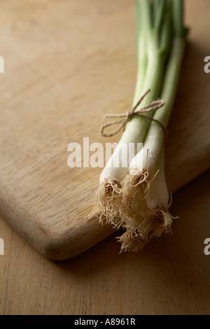 Spring onions or Scallions on a wooden chopping board Stock Photo