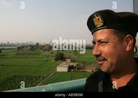 Policeman looking out over River Nile farmland and distant city skyline, Cairo, Egypt, Middle East Stock Photo