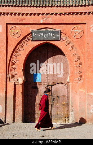 Woman dressed in traditional dress passes an oriental gate medina Marrakech Morocco Stock Photo
