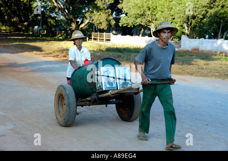 Man and woman carry drinking water in a barrel on a barrow Pindaya Shan State Burma Stock Photo