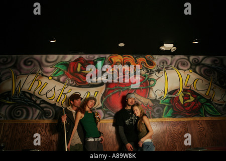 Two couples standing in front of a mural in a pool hall Stock Photo