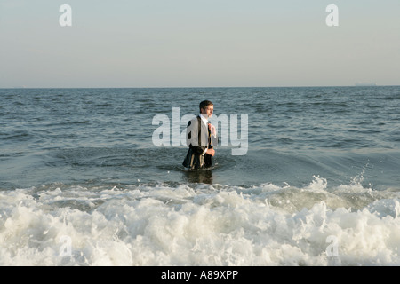 Man standing in ocean adjusting his tie Stock Photo