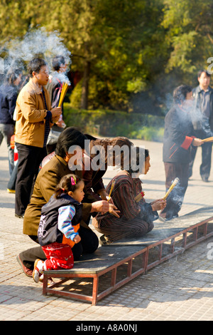 CHINA BEIJING Chinese Buddhists including a tiny girl toddler and her mother burn incense and kneel to pray Stock Photo