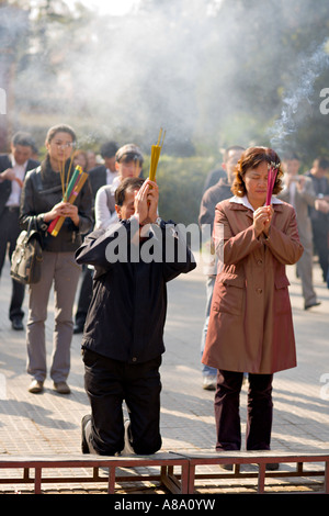 CHINA BEIJING Chinese Buddhists burn incense and kneel to pray outside the Palace of Peace and Harmony Yonghegong Lama Temple Stock Photo