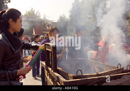 CHINA BEIJING Young Chinese Buddhists burn incense and pray outside the Palace of Peace and Harmony Yonghegong Lama Temple Stock Photo