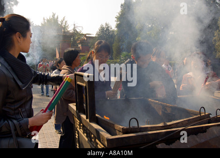 CHINA BEIJING Young Chinese Buddhists burn incense and pray outside the Palace of Peace and Harmony Yonghegong Lama Temple Stock Photo