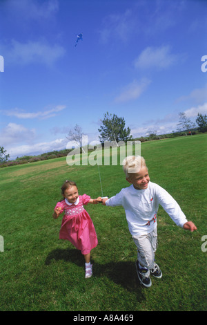 Boy and girl running with kite in park Stock Photo