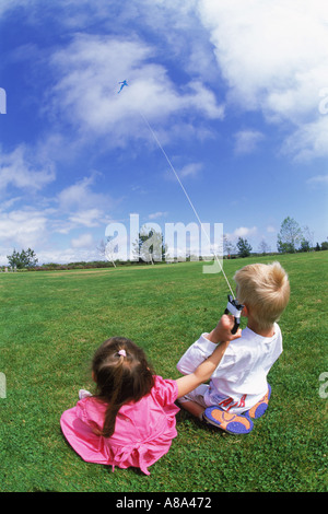 Boy and girl flying kite together in park Stock Photo