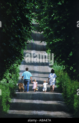 Family of four with dog on tree lined road in Sweden in summer Stock Photo