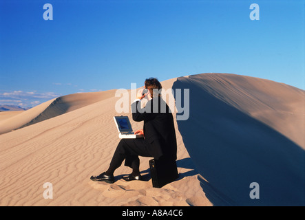 Businessman in desert with laptop computer talking on cellphone in his outdoor office Stock Photo