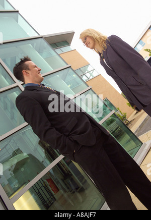 Angled shot of business professionals in smart suits facing each other outside a contemporary office block Stock Photo