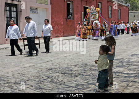 Children watching men and women wearing traditional costumes in a parade in Oaxaca Mexico Stock Photo