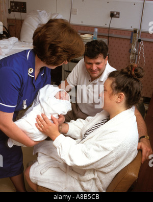 Agency nurse at Guys Hospital  London handing over a baby to a young couple. Stock Photo