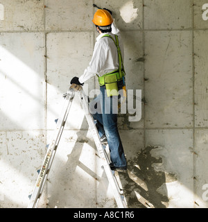 at a construction place a worker working on a ladder Stock Photo