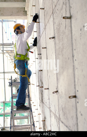 at a construction place a worker working on a ladder Stock Photo