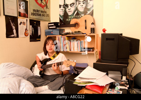 12 Year Old Boy Practising Guitar In His Bedroom Stock Photo