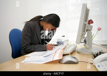 paye tax documents being completed by stressed korean asian woman employee Stock Photo
