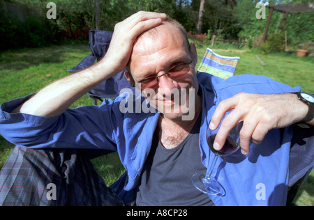 middle aged man relaxing with glass of wine in garden Stock Photo