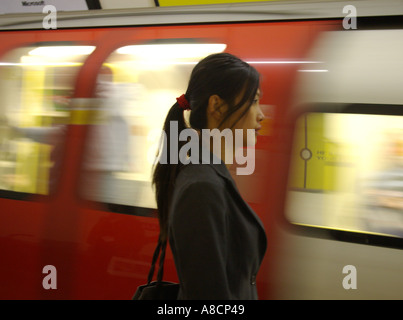 tranquil attractive Korean oriental asian female and blurred speeding London tube train in background Stock Photo