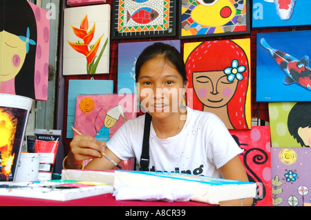 Thailand Bangkok Chatuchak Weekend Market Young female artist working on her painting in her small shop Stock Photo