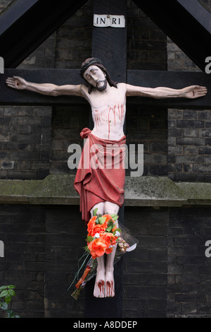 A grubby crucifix effigy of Jesus Christ on the cross is attached to a church wall in Camden North London Stock Photo