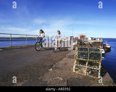 dh Longhope HOY ORKNEY Children riding bicycles on South Ness pier outdoor uk kids cycling child two girls cycle 2 young people Scotland Stock Photo